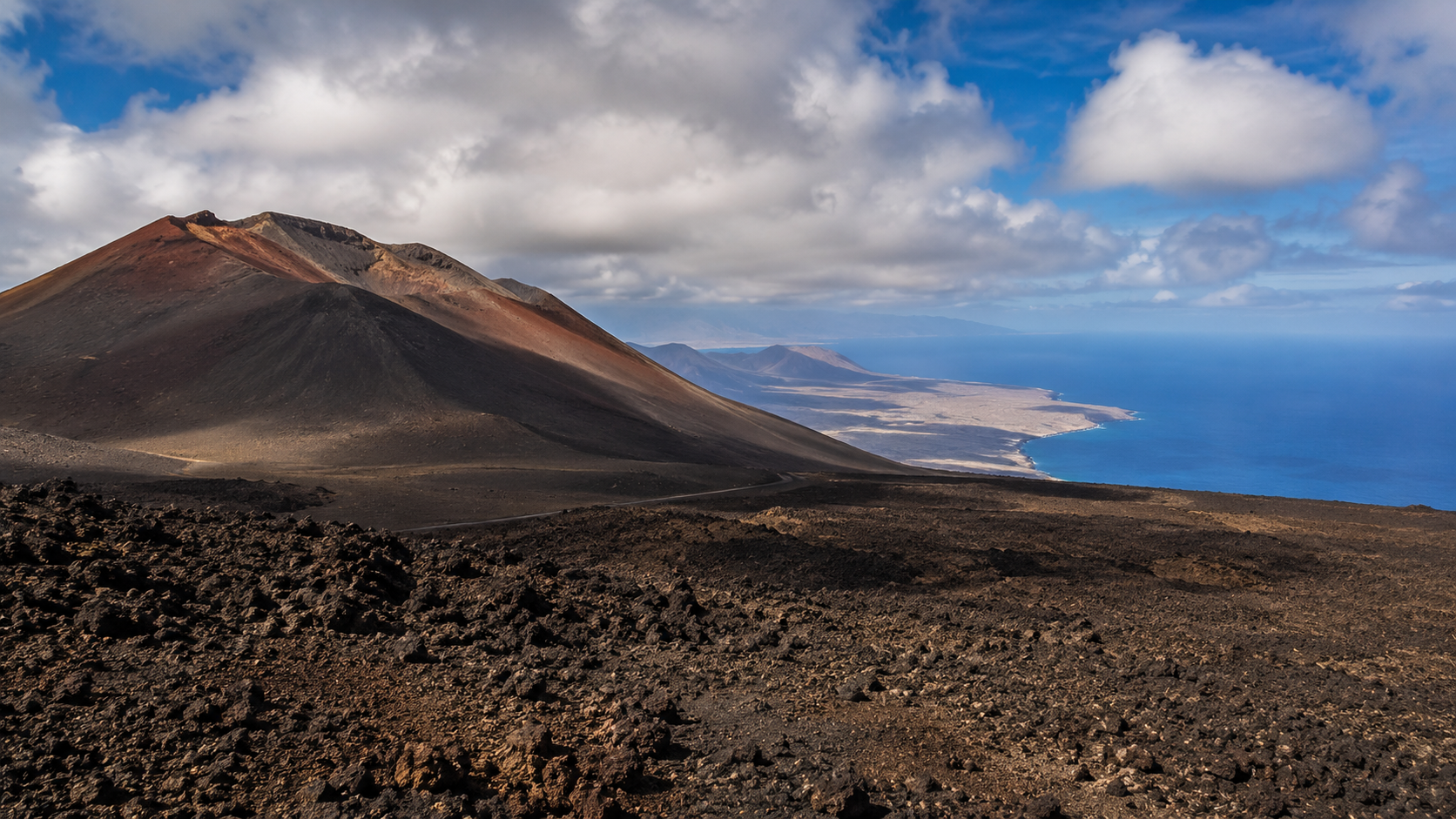 Volcanic landscape in the Canary Islands with lava fields and ocean views.