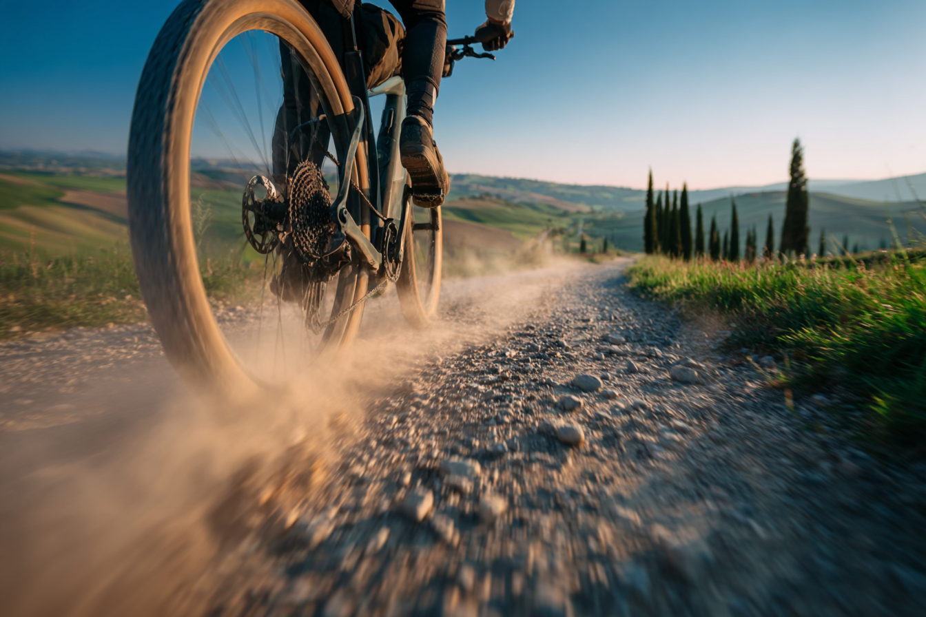 A cyclist riding on the white gravel roads of Tuscany near Val d'Orcia, a top destination for active travel in Italy.