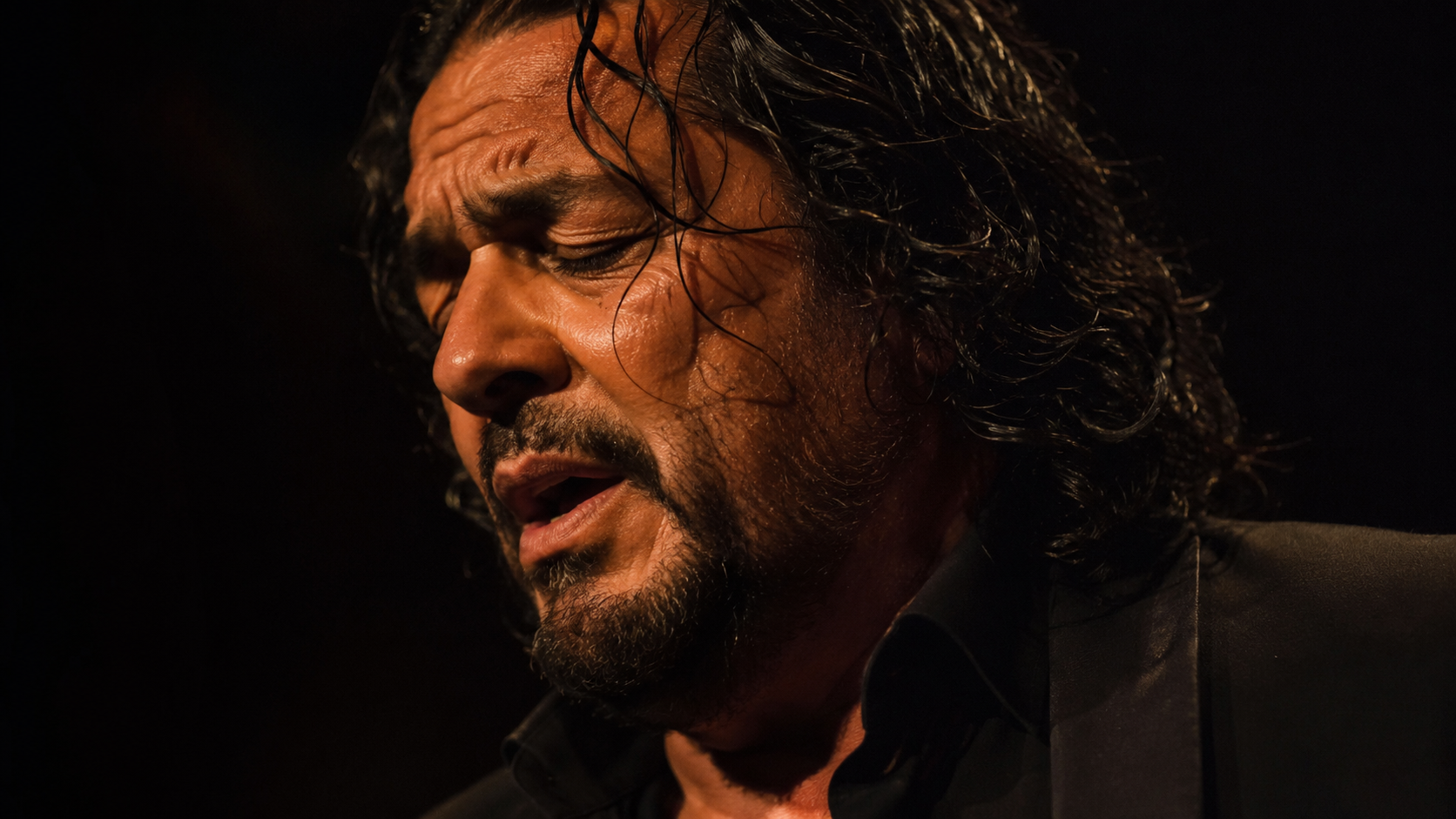 Flamenco singer expressing duende under warm stage light.