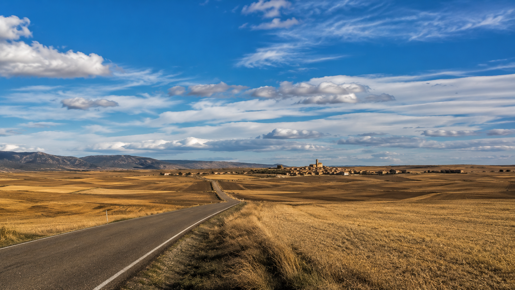 Vast inland Spanish plateau with golden fields and a big open sky.