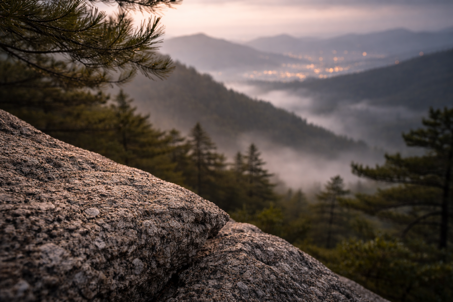 Textures of granite and pine fading into a foggy valley, calm and cinematic.