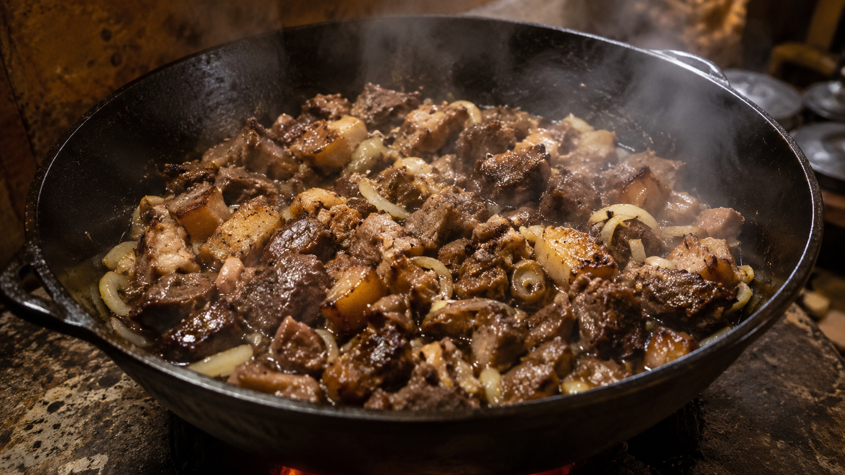 Kuyrdak cooking in a heavy pan with onions and warm firelight.
