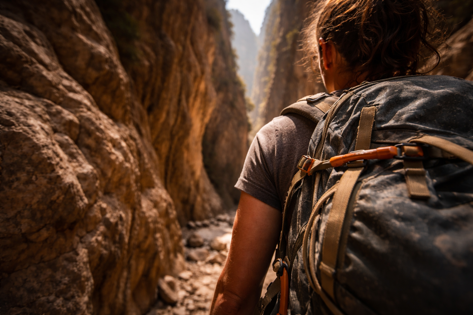 Hiker moving through steep gorge walls in a dramatic Cretan landscape.
