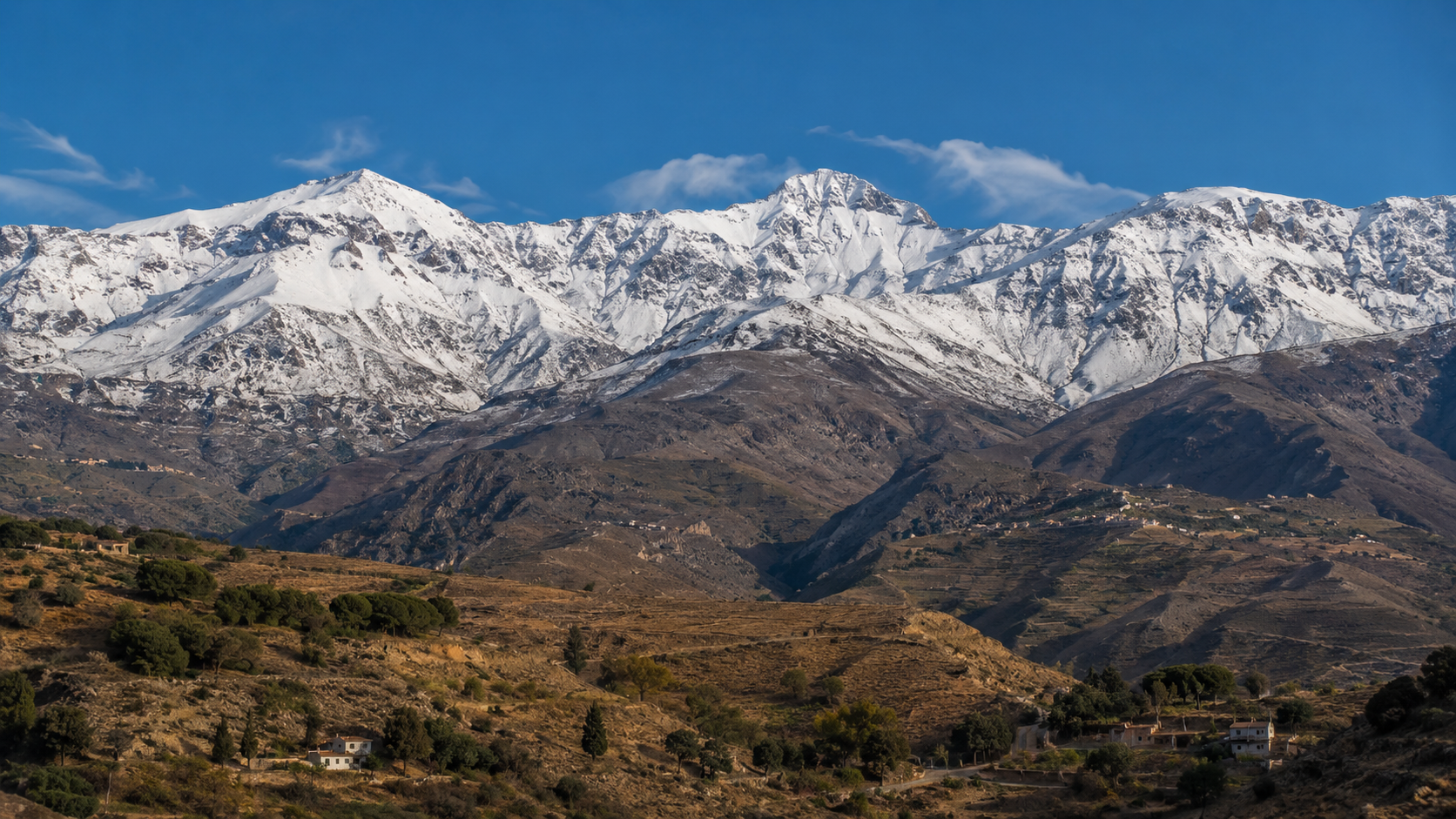 Snowy Sierra Nevada peaks rising above Andalusian foothills.